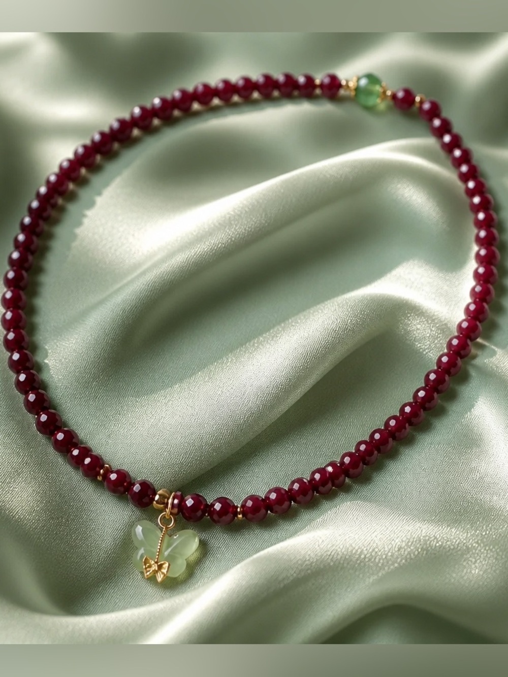 beaded necklace , deep red garnet stones and a delicate green butterfly pendant